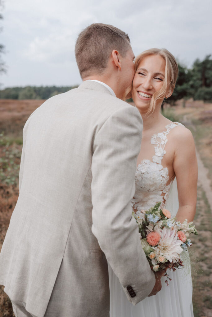 Braut und Braeutigam lachen waehrend ihres Brautpaarshootings auf Gut Horn. Emotionale Hochzeitsfotografie in der Natur mit pastellfarbenem Brautstrauss vom Hochzeitsfotograf Oldenburg.