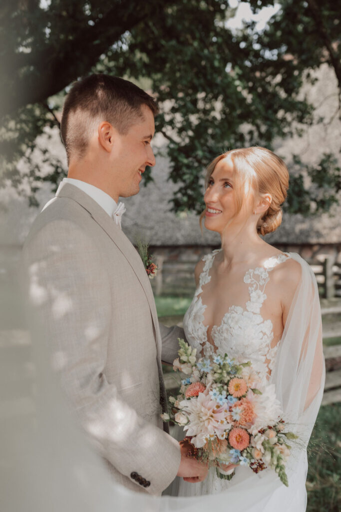 Brautpaar blickt sich beim Brautpaarshooting auf Hof Schweers in Oldenburg verliebt an – natürliche Hochzeitsfotografie von einem Hochzeitsfotografen aus Oldenburg.